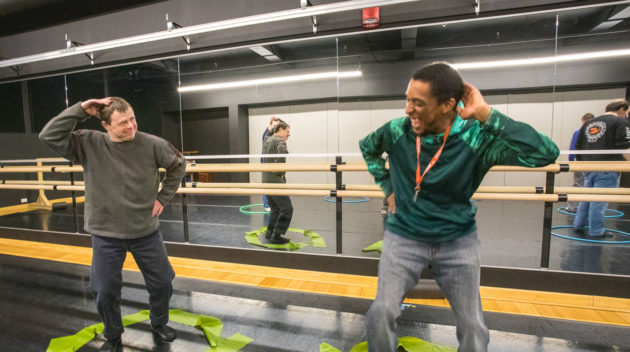 two adults dancing in hula hoops on the floor.