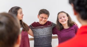 kids happily leaning on eachother in improv class.