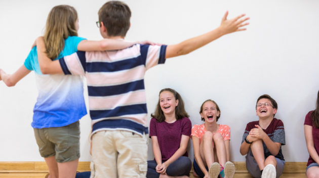 two kids performing improv in front of three other kids.