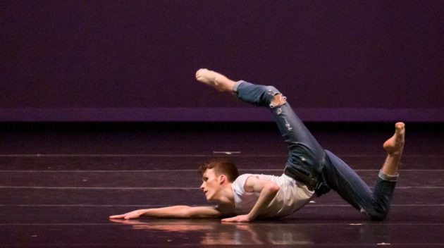 Contemporary dancer mid performance laying out on stage.