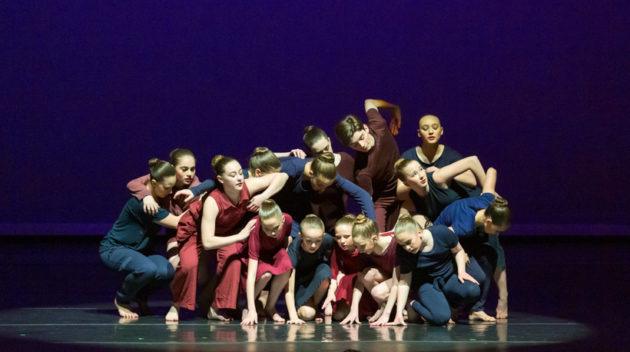 group of dancers piled up on stage mid performance.