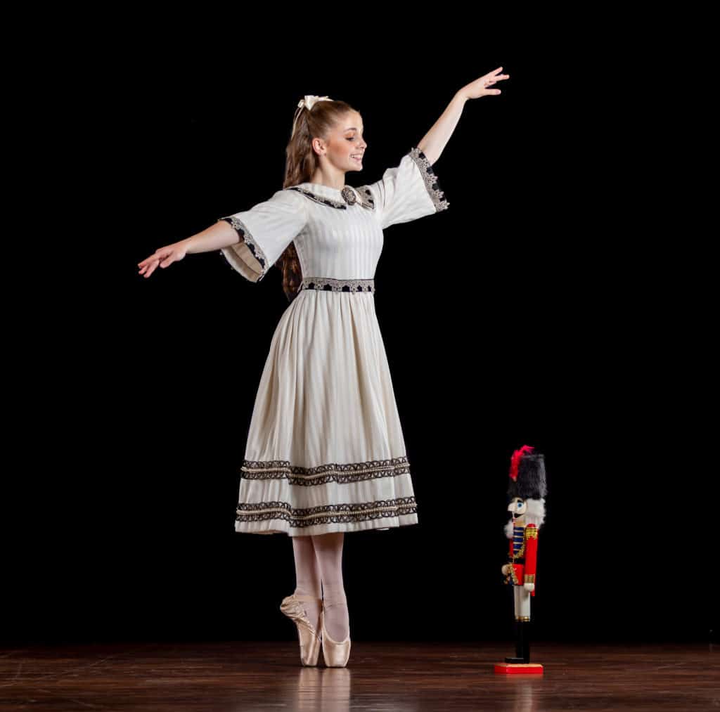 Morgan Soulé is posed in an sous-sus in her pointe shoes. She is gazing down at the nutcracker beside her.