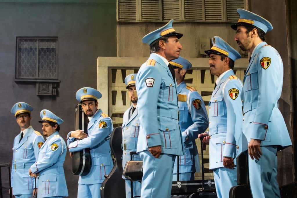 Members of the Egyptian police orchestra from The Band's Visit are standing in a line, looking to their conductor.