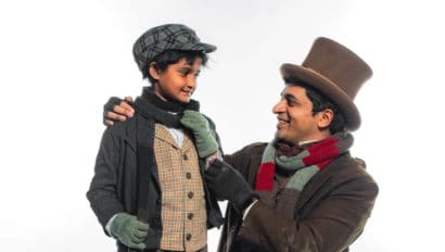 Sri and Sriram pose together for a picture in costume as their characters. Both of the actors are wearing wintery clothing with scarfs and mittens. Sriram is wearing a tophat.