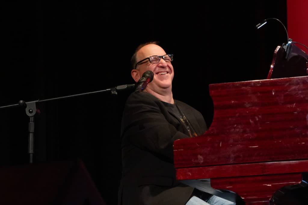 Neil Berg is grinning ear-to-ear as he plays the piano. 