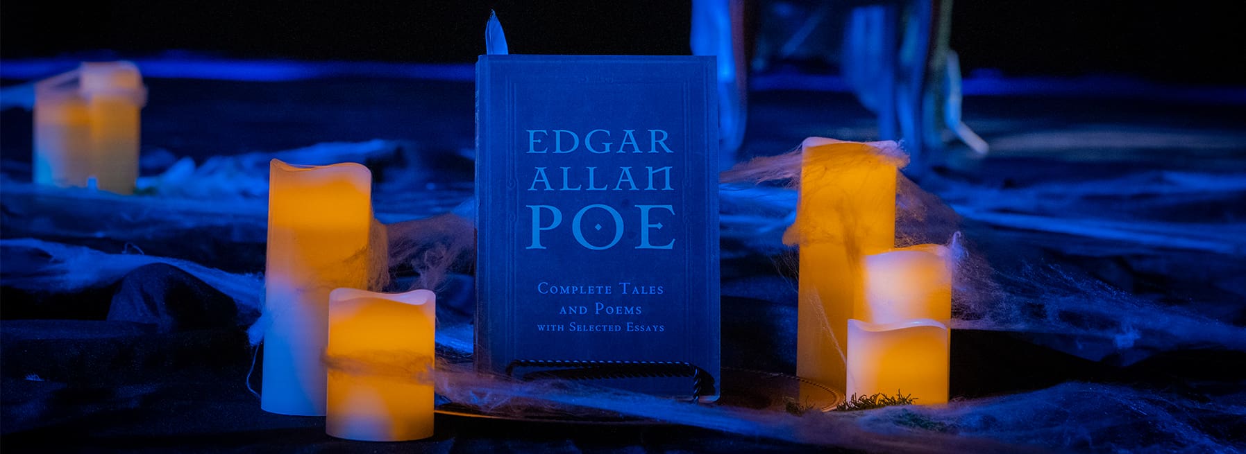 Candles surrounding Edgar Allan Poe's "Complete Tales and Poems with Selected Essays"