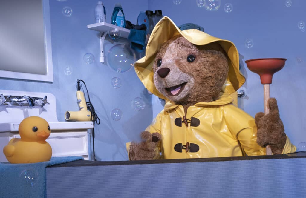 Puppet Paddington Bear in bath tub wearing yellow rain coat