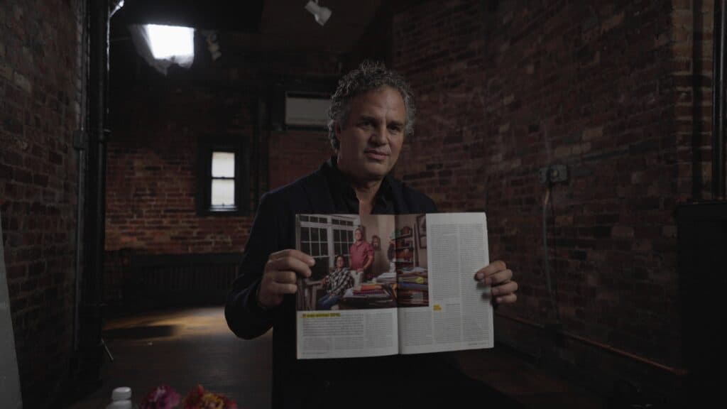 Mark Ruffalo holds up a magazine article about Diane and Paul Cotter.
