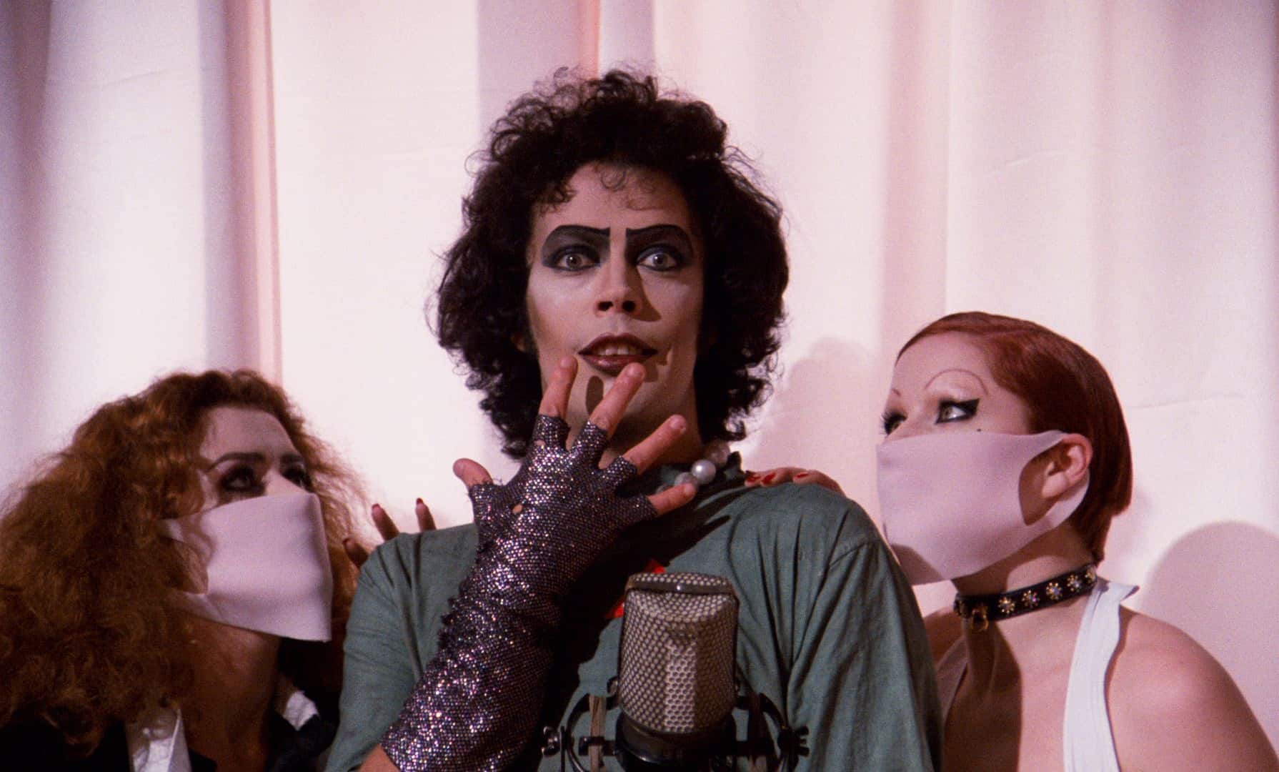 Dr Frankenfurter stands with two people on either side of him, he wears a green scrubs and gloves.
