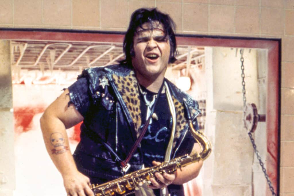 Meat Loaf as Eddie plays the saxophone with a leopard leather jacket on.