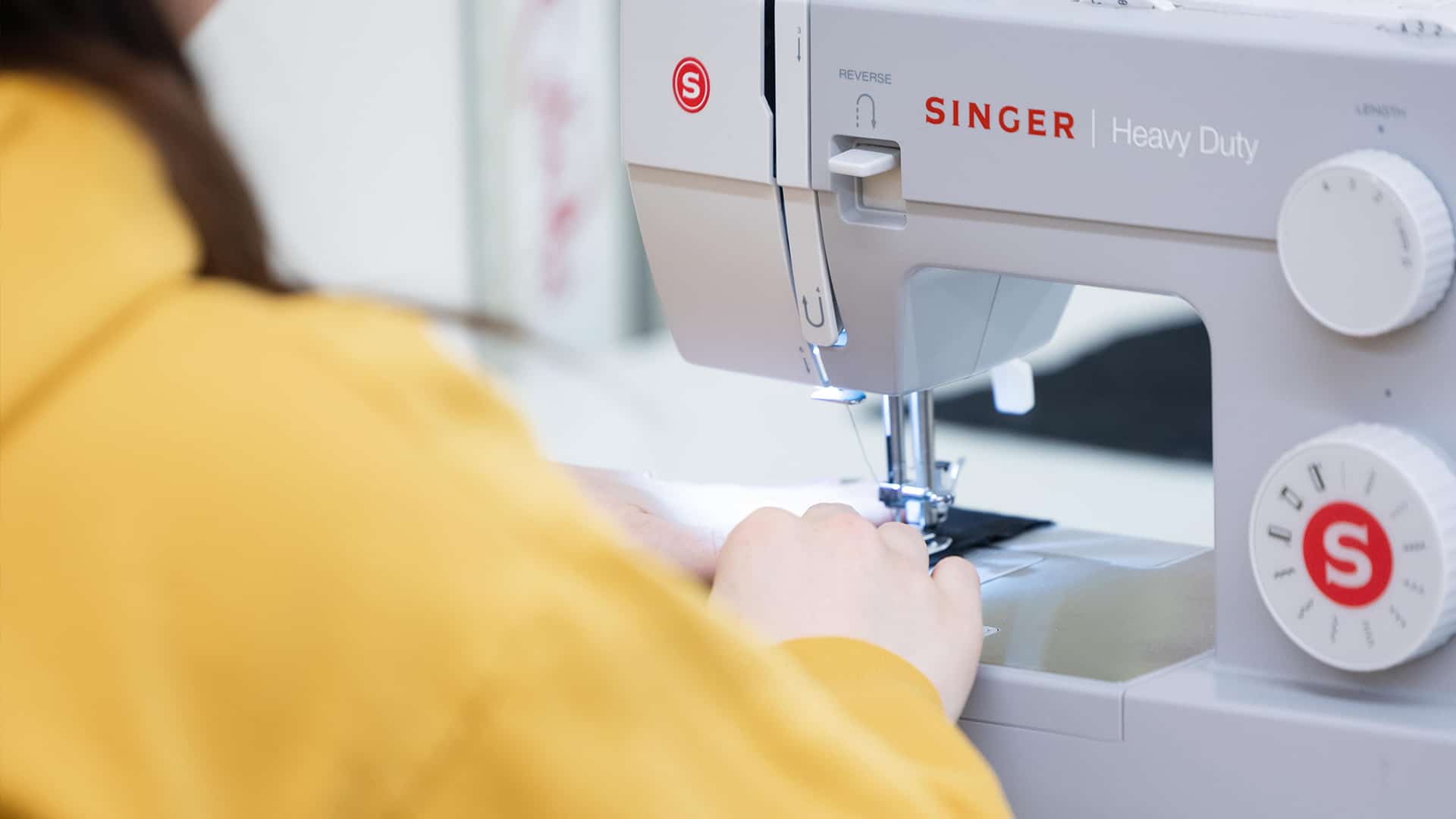 a costume design student sits at a sewing machine working on a piece