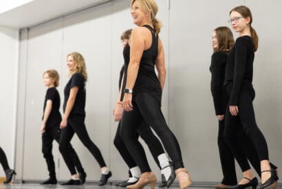 Eight dancers in Modern II (Ages 15+) all wearing black and posed, looking off camera.