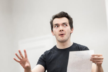 Adult Acting Workshop Ages 18+ - Hanover Theatre and Conservatory Young man in a black T-shirt gesturing with his left hand while holding a paper, speaking or presenting.