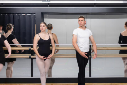 Adult Ballet Beginner Ages 18+ SUMMER - Hanover Theatre and Conservatory Group of ballet students at a barre in a studio, wearing black leotards and tights, focusing on pose.