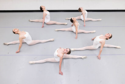 Flexibilty and Strength Training for Dancers SUMMER - Hanover Theatre and Conservatory Six ballet dancers in white leotards in full side splits on a gray dance floor