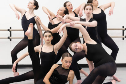 Intermediate/Advanced Contemporary SUMMER - Hanover Theatre and Conservatory Group of ballet dancers in black leotards stretching around a barre in a studio."