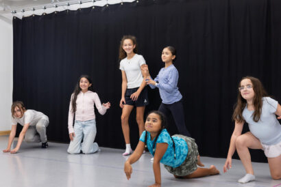 Physical Comedy for Kids Grades 5-8 - Hanover Theatre and Conservatory Diverse group of children practicing a dance routine in a studio with a black curtain backdrop.