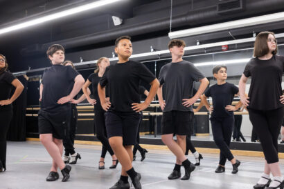 Teen Musical Theatre Dance SUMMER - Hanover Theatre and Conservatory Group of young dancers in black practice attire standing in a studio with hands on hips, posing in formation.