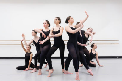 Contemporary 2 Ages 13+ - Hanover Theatre and Conservatory Group of ballerinas in black leotards posing during a ballet rehearsal in a studio with a barre along the wall.