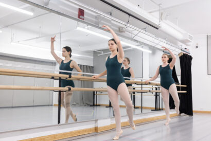 Teen Ballet Beginner 2 Ages 12-18 - Hanover Theatre and Conservatory Three ballerinas in teal leotards练 at a barre in a bright dance studio, mirrored wall reflecting their pose.