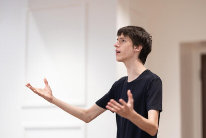 Voice and Speech Teens Adults - Hanover Theatre and Conservatory Young man in a dark t-shirt gesturing with hands while speaking in a bright room