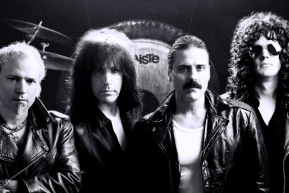 AQ_1920 x 1080 hero image - video card - FB event - Hanover Theatre and Conservatory Four male rock musicians in leather jackets posing in a studio with a drum kit behind them, black-and-white photo.