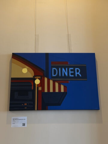 Neon-lit diner sign against a blue sky with a storefront awning and warm street lamp lights.