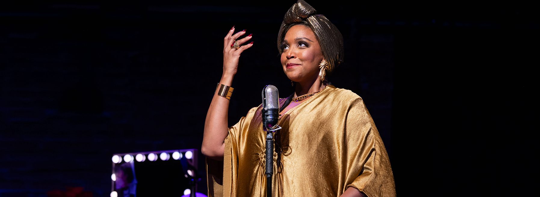 Who Is Eartha Mae? - Hanover Theatre and Conservatory - Hanover Theatre and Conservatory African American woman singer at a microphone on stage, wearing a gold metallic outfit and headwrap, mid-performance.